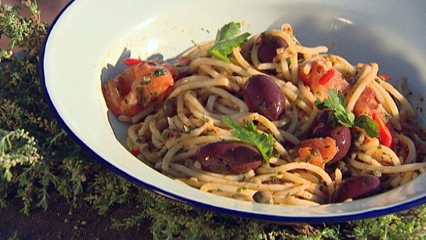 Spaghetti tossed in a wok with olives, anchovies and capers