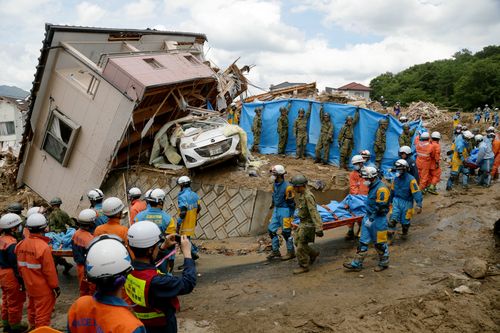 A victim is carried away by Japanese police and  Ground Self-Defense Force rescue workers after they were killed in a landslide. Picture: AP