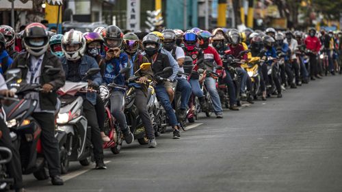 Motorcyclists outside Manila queue up for a health check before they are allowed into the city.