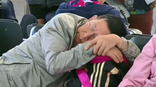 A man sleeps as passengers are hit with significant delays in Sydney Airport.
