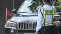 A security guard signals to a car with diplomatic plates and Chinese flag as he parks at the Philippine Department of Foreign Affairs in Manila, Philippines on Aug. 7, 2023.