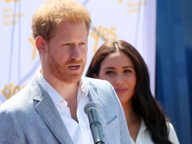 Prince Harry delivers a speech during the royal tour of Africa while wife Meghan Markle looks on.