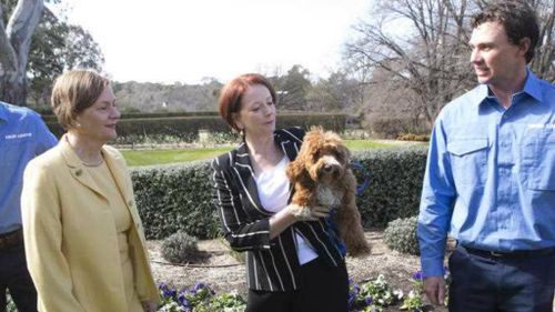 Then Prime Minister Julia Gillard and her dog Reuben pose for a photograph with Lodge gardeners on the grounds. (AAP)