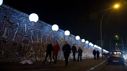 People pass by balloons used in an art project next to remains of the Berlin Wall in Germany. (AAP)