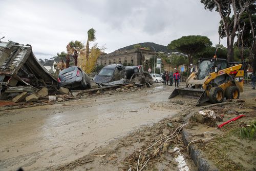 Los rescatistas limpian el lodo de una calle después de que las fuertes lluvias provocaran deslizamientos de tierra en Italia.