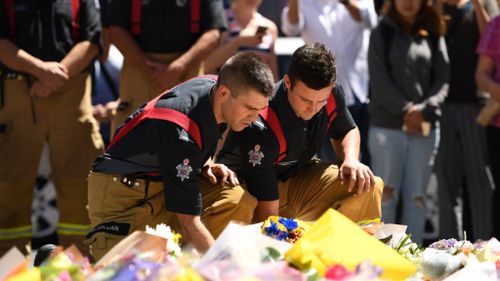 Firefighters leave flowers at the corner of Bourke and Elizabeth streets. (9NEWS)