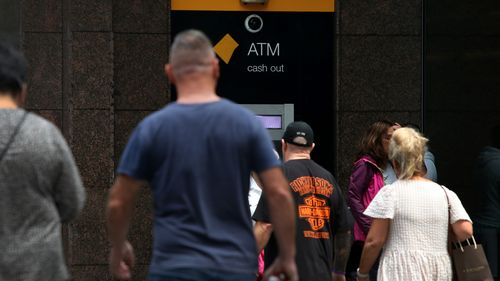 People move past a Commonwealth Bank ATM machine.