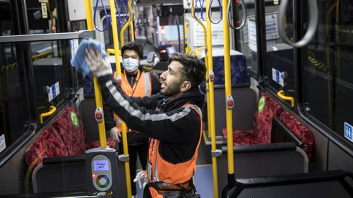 Workers clean a bus in Sydney to prevent the spread of COVID-19.