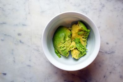Avocado in a white bowl with a white marble chopping board