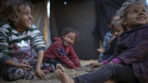 Grandchildren of Reda Abu Zarada, displaced from Jabaliya in northern Gaza, play next to their tent at a camp in Khan Younis, Gaza Strip, Thursday, Dec. 19, 2024. (AP Photo/Abdel Kareem Hana)