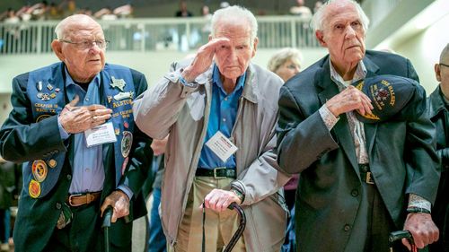 Pearl Harbor survivors, J.C. Alston, 94, and Jim Leavelle, 97, along with World War II veteran Sam Sorenson, stand for the national anthem at the Pearl Harbor Remembrance Ceremony at the National Museum of the Pacific War in Fredericksburg, Texas. (AAP)