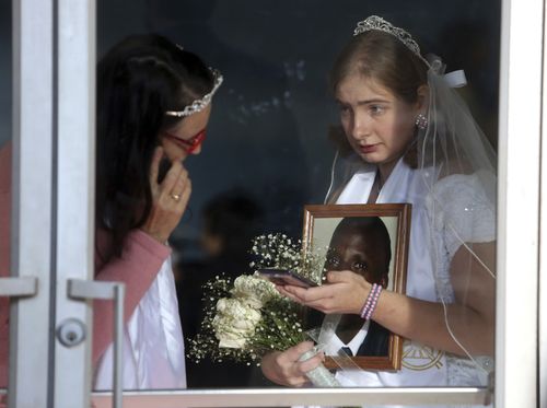 The worshippers gathered to be part of a commitment ceremony between brides in white dresses and grooms in dark suits. (AAP)