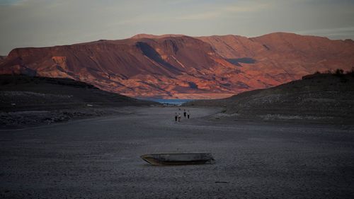 A formerly sunken boat sits on cracked earth hundreds of feet from what is now the shoreline on Lake Mead at the Lake Mead National Recreation Area.