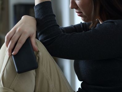 Sad woman holding smart phone complaining at home