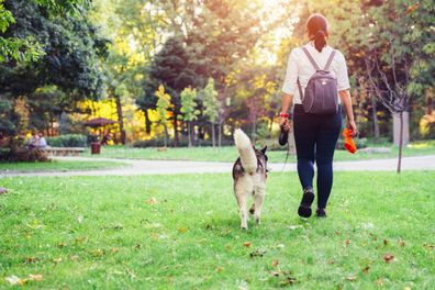 Woman with her dog in the city park holding poop bag