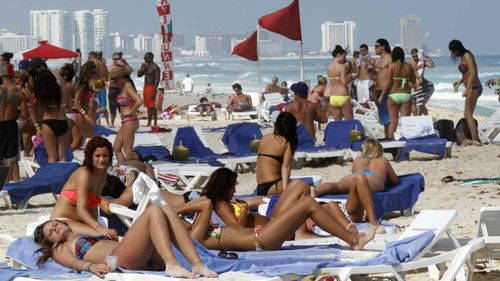 Tourists lie in the sun on the beach in Cancun.