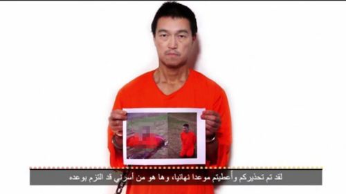 Japanese hostage Kenji Goto holding a photo purporting to show the body of his fellow prisoner Haruna Yukawa. (Supplied)