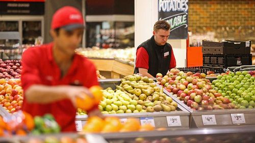 Coles staff restock shelves ahead of opening time.