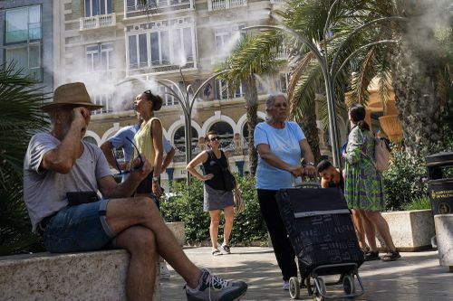 People take advantage of water mist fountains in Valencia, Spain on June 21, 2025, as parts of the country experience a heatwave.