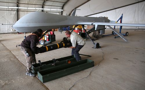 Contract workers load a Hellfire missile onto a US Air Force MQ-1B Predator unmanned aerial vehicle (UAV), at a secret air base in the Persian Gulf region. The US military and coalition forces use the base, located in an undisclosed location, to launch drone airstrikes against Islamic State in Iraq and Syria.