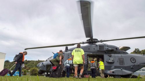 People walk to a helicopter with their suitcases as hundreds of tourists are evacuated from Kaikoura. (AFP / New Zealand Defence Force)