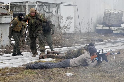 An instructor, second left, runs during a training for civilians and members of the Georgian Legion, a paramilitary unit formed mainly by ethnic Georgian volunteers to fight against the Russian aggression in Ukraine in 2014, in Kyiv, Ukraine, Saturday, Feb. 19, 2022. 