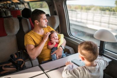 Father traveling by train with his two kids