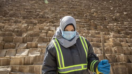 A municipal worker cleans at the Giza Pyramids as a prevention measure due to the coronavirus outbreak, in Giza,  Egypt, Wednesday, March 25, 2020. 