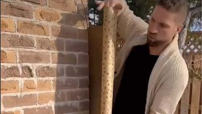 Man wrapping the outside of his house with wrapping paper