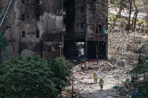 Firefighters walk through the burned buildings after the deadly fire in Hong Kong's New Territories.