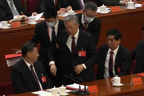 Former Chinese President Hu Jintao, centre, is helped during the closing ceremony of the 20th National Congress of China's ruling Communist Party at the Great Hall of the People in Beijing, Saturday, Oct. 22, 2022.  