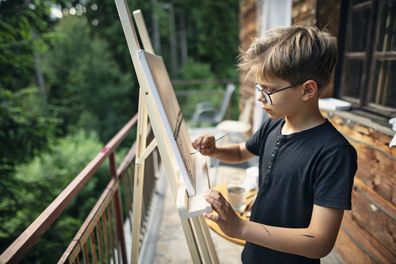 Little boy painting on easel. 