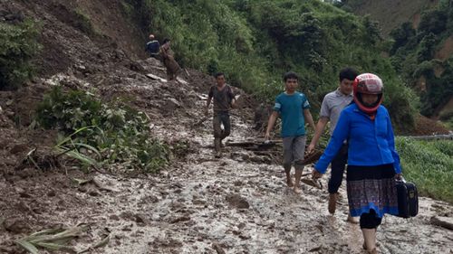 Residents walk through a muddy road which was damaged by a landslide in northern province of Son La, Vietnam (Huu Quyet/Vietnam News Agency via AP).