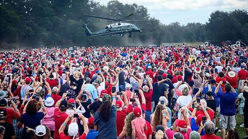 Amid a sea of red, blue and white a packed crowd raise react to Donald Trump's presidential chopper arriving in Florida.