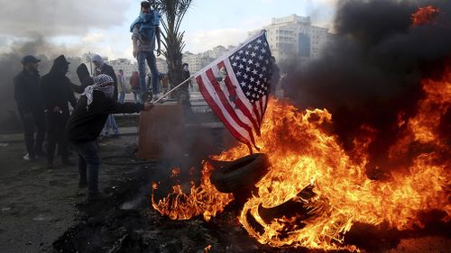 Palestinians protester burn the US flag during clashes with Israeli soldiers. (AAP)