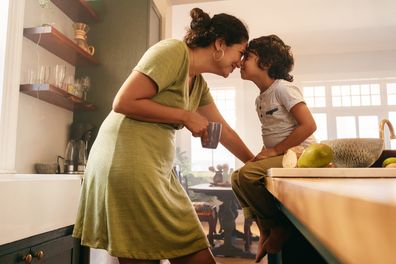 Affectionate mother touching noses with her young son in the kitchen. Cheerful mother and son looking at each other fondly. Loving single mother bonding with her son at home.