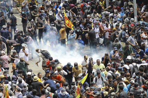 Protesters react as a tear gas shell fired by police lands next to them in Colombo, Sri Lanka, Saturday, July 9, 2022. 