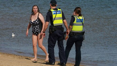 Police officers inform beachgoers that the beach is closed at St Kilda Beach in Melbourne, Saturday, March 28, 2020. 
