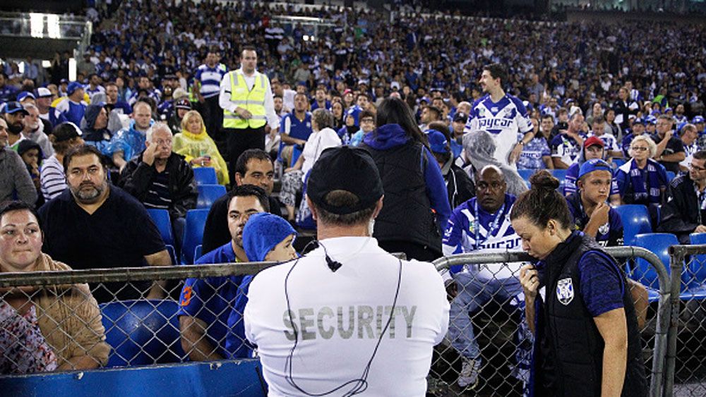A security guard watches the crowd following the bottle throwing incident at Belmore Oval. (Getty) 