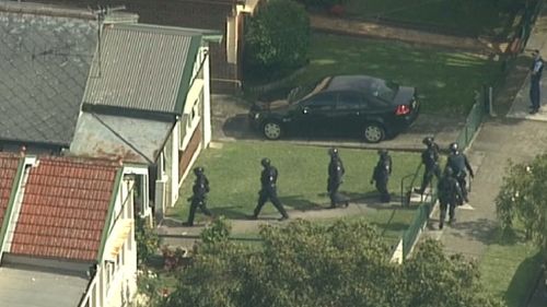 Armed officers enter a Lakemba home yesterday. (9NEWS)