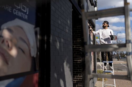 Adam Hameed, paints the exterior of a skin care center, Wednesday, Nov. 6, 2024, in Dearborn, Mich, the nation's largest Arab-majority city.  