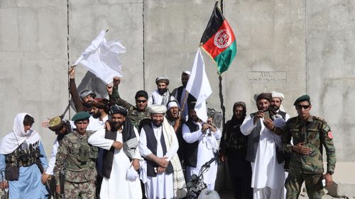 Afghan civilians carrying Afghan national flag along with Taliban flag stand with Taliban fighters and army soldiers. Picture: EPA