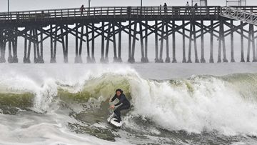 A surfer rides a wave at Seal Beach, Calif., Monday, Dec. 23, 2024. (Jeff Gritchen/The Orange County Register via AP)