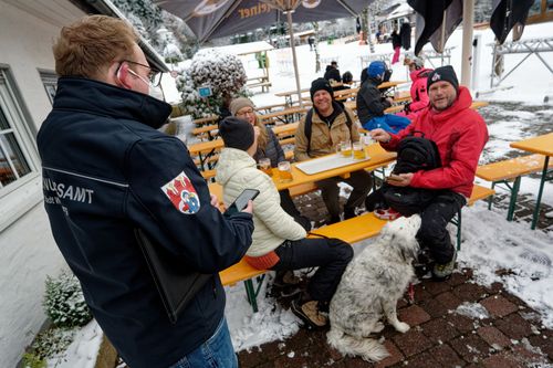 Un funzionario dell'ordine pubblico controlla i certificati di vaccinazione COVID-19 degli sciatori sulla pista da sci Rauher Busch a Winterberg, in Germania, sabato 27 novembre 2021.
