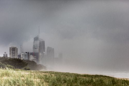 Heavy rain has lashed the Gold Coast, as huge swells forced the closure of beaches.