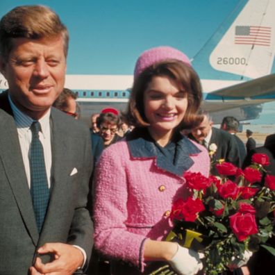 President John F. Kennedy and his wife Jackie, who is holding a bouquet of roses, just after their arrival at the airport for the fateful drive through Dallas.