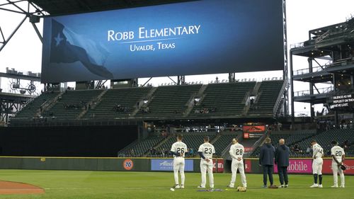 Seattle Mariners players stand on the field before a baseball game against the Oakland Athletics at T-Mobile Park during a moment of silence for the victims of a shooting at Robb Elementary School in Uvalde, Texas.