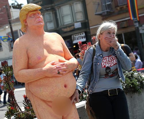 A passerby has a picture taken with a statue depicting republican presidential nominee Donald Trump in the nude on August 18, 2016 in San Francisco, United States. (AFP)