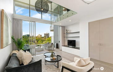 A light-filled Brisbane apartment featuring double-height ceilings, a glass mezzanine, and floor-to-ceiling city views.