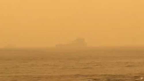 The HMAS Choules is barely visible from shore.